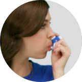 Woman breathing into application device ONZETRA® Xsail® (sumatriptan nasal powder)