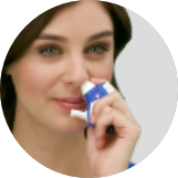 Woman using application device ONZETRA® Xsail® (sumatriptan nasal powder)